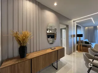 Hall de entrada com painel de madeira e espelho decorativo.