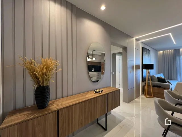 Hall de entrada com painel de madeira e espelho decorativo.
