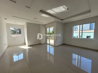 Sala de estar ampla com piso de porcelanato claro e grandes janelas.