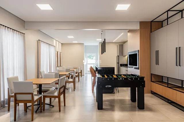 Sala de jantar com mesa de madeira e cozinha moderna em um imóvel no Brasil.