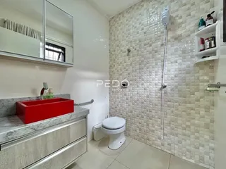 Banheiro com revestimento de azulejo e bancada de mármore.