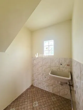 Canto interno de um ambiente com paredes e piso revestidos de cerâmica.