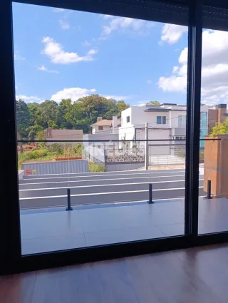 Vista da propriedade com paisagem verde e um edifício ao fundo.