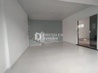 Interior de um espaço vazio com paredes brancas e piso claro.