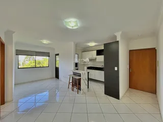 Ambiente interno de uma sala de estar com piso de cerâmica e cozinha moderna.