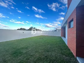 Vista externa da propriedade com gramado e muro branco.