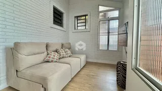 Sala de estar com sofá e piso de madeira clara em uma residência.