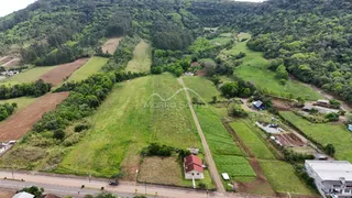 Vista aérea de uma propriedade rural com campos verdes e vegetação densa ao fundo.