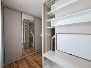 Hall de entrada com piso de madeira e espelho na sala.