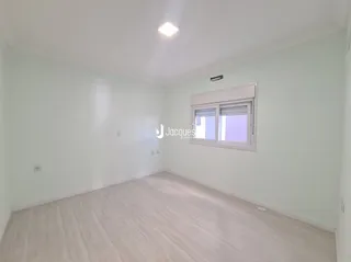 Ambiente interno de uma sala com piso de madeira clara e janela.