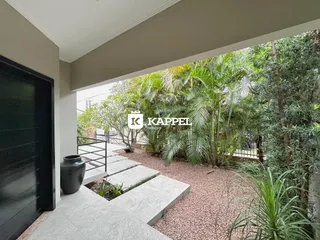Vista do jardim externo com vegetação tropical e um caminho de concreto.