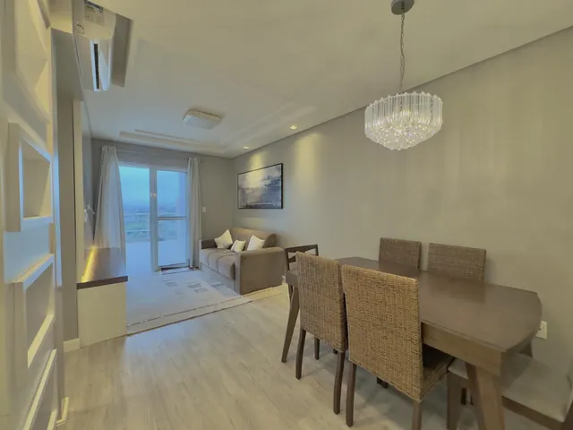 Sala de estar com sofá e mesa de jantar em um ambiente claro.