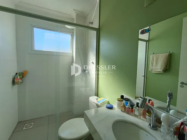 Banheiro com box de vidro e pia de mármore.
