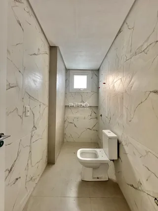 Hall de banheiro com revestimento de mármore nas paredes.