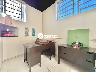 Um cômodo interno com grandes janelas e móveis de madeira escura.