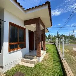 Fachada de uma residência em Lajeado, Brasil, apresentando paredes brancas e detalhes em alvenaria de tijolo aparente.