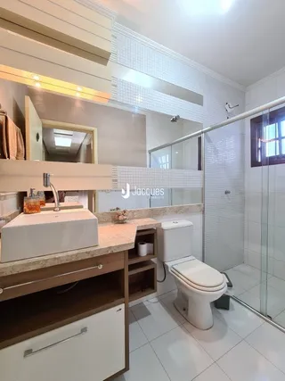 Foto de um banheiro interno com azulejos brancos e louças sanitárias.