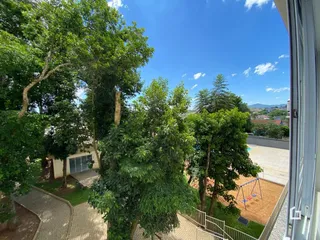 Vista externa da propriedade com árvores frondosas e área externa.