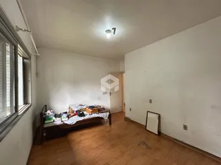 Um quarto com piso de madeira e janela.