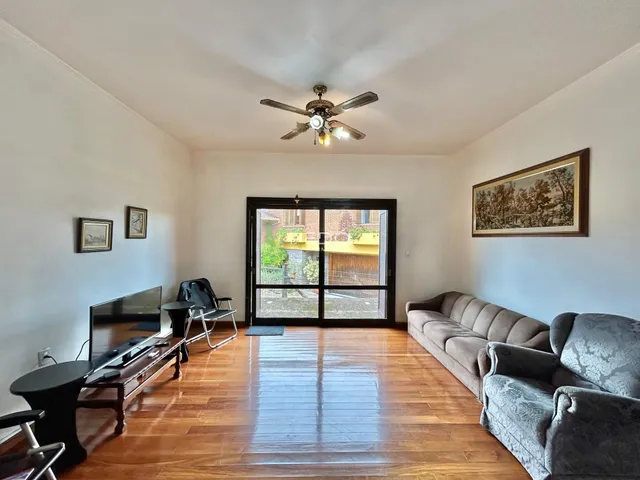 Sala de estar com piso de madeira e porta de vidro abrindo para o exterior.