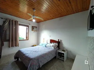 Quarto com teto de madeira e janela no interior de uma residência.