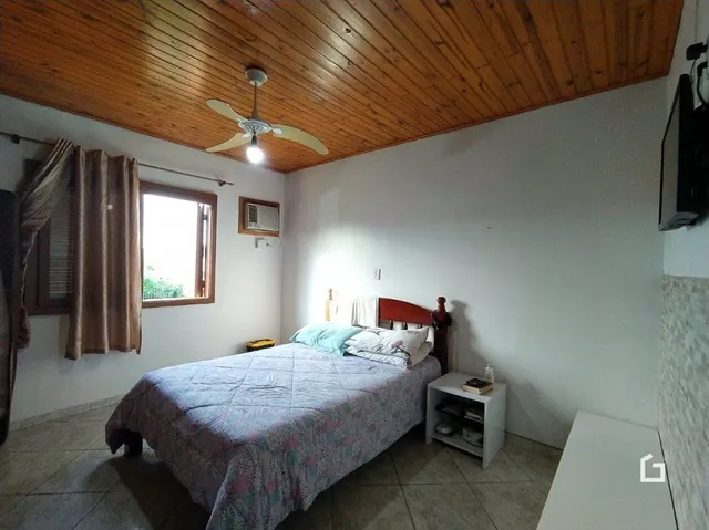 Quarto com teto de madeira e janela no interior de uma residência.