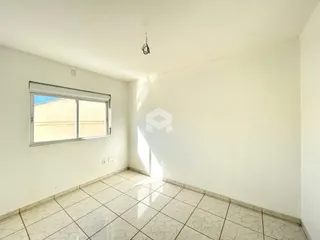Interior de um cômodo com paredes brancas e piso de cerâmica clara.