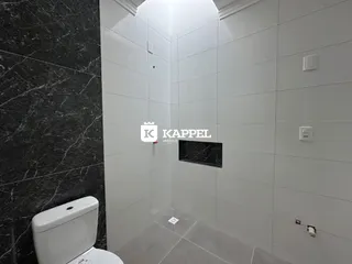 Banheiro com revestimento branco e piso claro.