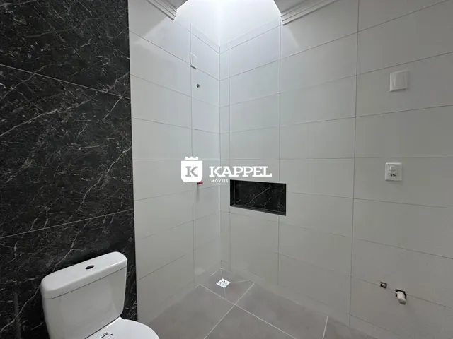 Banheiro com revestimento branco e piso claro.