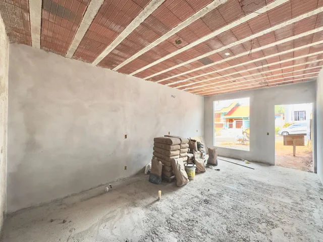 Foto de um ambiente interno em fase de construção com paredes e teto expostos.