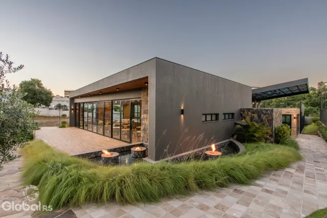 Fachada moderna de uma residência em Lajeado, Brasil, com área externa pavimentada e jardim.