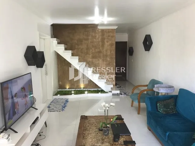 Sala de estar com escadaria e televisão em um imóvel no Brasil.