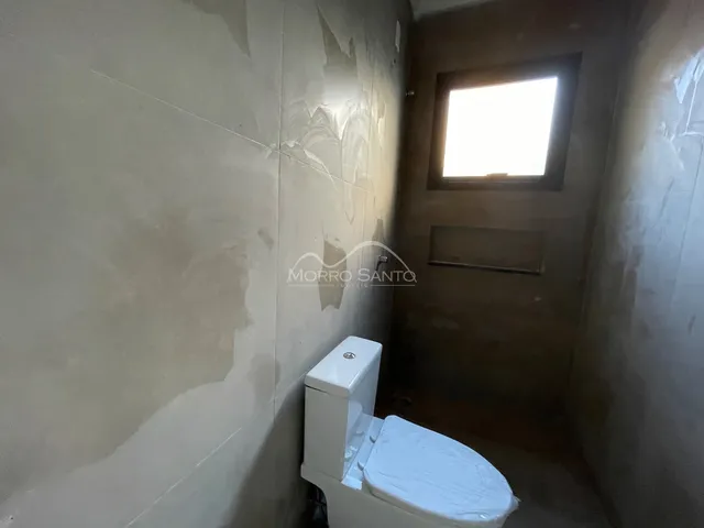 Banheiro com vaso sanitário branco em um corredor.