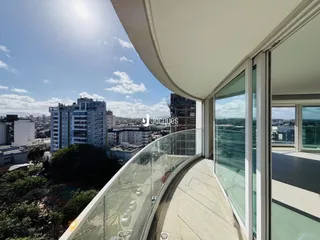 Vista panorâmica de uma varanda com grade de vidro de um edifício moderno.