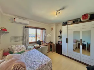 Quarto com piso de madeira e armários brancos.