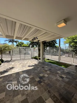 Área externa pavimentada com piso de ladrilhos e cerca de metal.