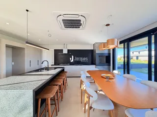 Cozinha e sala de jantar moderna com ilha e mesa de madeira.