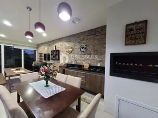Ambiente interno de sala de jantar com parede de tijolos aparentes.