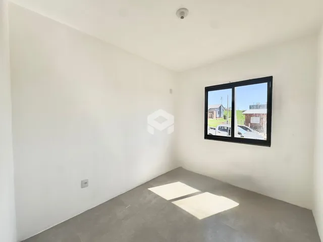 Ambiente interno de uma sala com paredes brancas e piso de concreto.
