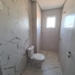 Foto de um corredor interno com paredes brancas e piso de azulejo claro.