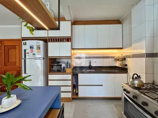 Cozinha moderna com armários brancos e bancada escura.
