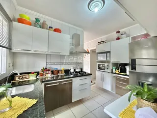 Cozinha moderna com armários brancos e bancadas escuras.