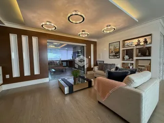 Sala de estar ampla com piso de madeira e decoração elegante.