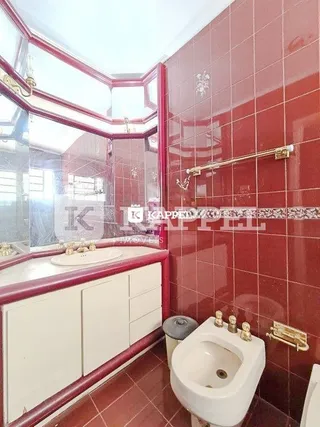 Foto interna de um banheiro com revestimento de azulejos vermelhos.