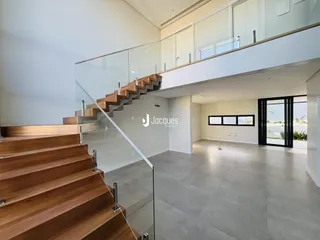 Vista interna de uma escadaria com guarda-corpo de vidro em um imóvel.