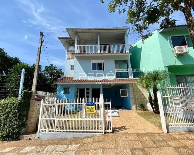 Fachada de uma casa azul em Lajeado, Brasil, com cerca e portão de madeira.