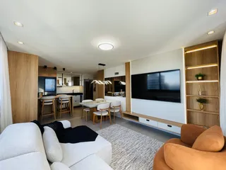 Sala de estar e cozinha moderna com acabamentos em madeira.