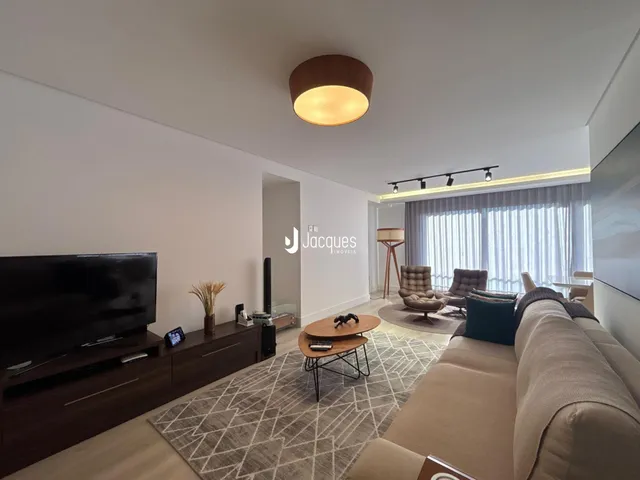 Sala de estar moderna com sofá e televisão em um ambiente claro.
