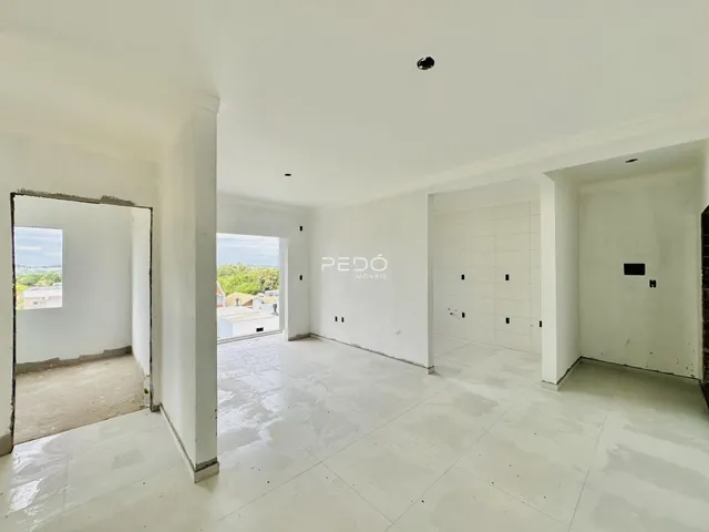 Vista interna de um espaço amplo com paredes brancas e piso claro.