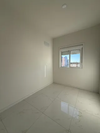 Ambiente interno com piso de mármore claro e janela na parede.